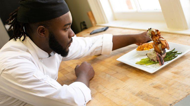 Male student chef plates a dis